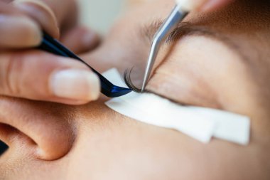 Kirpik uzatma işleminde orta yaşlı güzel bir kadın. Kozmetik ve vücut bakımı yakın çekim. Sığ alan derinliği ve seçici odak.