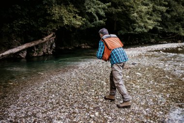 Kıdemli adam hızlı dağ nehrinde tek başına balık tutuyor. Aktif insanlar ve balıkçılık konsepti.