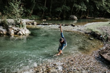 Kıdemli adam hızlı dağ nehrinde tek başına balık tutuyor. Canlı bir alabalık tutuyor ve tekrar nehre salmadan önce onu öpüyor..