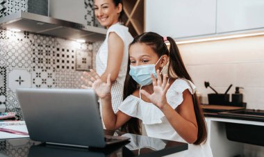Genç bir anne, Covid-19 salgını sırasında ya da karantina sırasında kızına e-öğrenim oturumunda yardım ediyor. Hastalık önleme ve yeni normal kavram.
