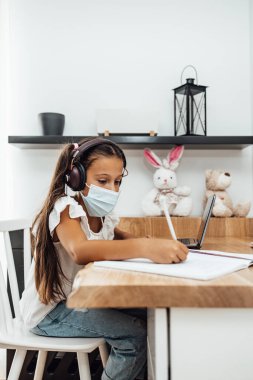 Covid-19 salgını sırasında ya da karantina sırasında e-öğrenim seansı yapan küçük bir kız. Hastalık önleme ve yeni normal kavram.