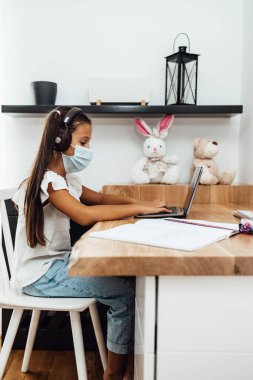 Covid-19 salgını sırasında ya da karantina sırasında e-öğrenim seansı yapan küçük bir kız. Hastalık önleme ve yeni normal kavram.
