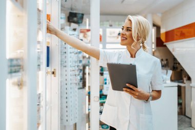 Bir eczanede çalışan genç ve çekici bir kadın eczacı. Mutlu ve gülümsüyor..