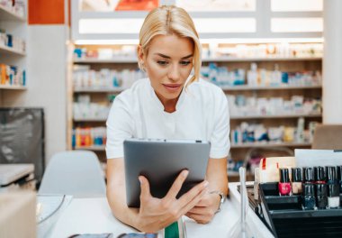 Bir eczanede çalışan genç ve çekici bir kadın eczacı. Mutlu ve gülümsüyor..