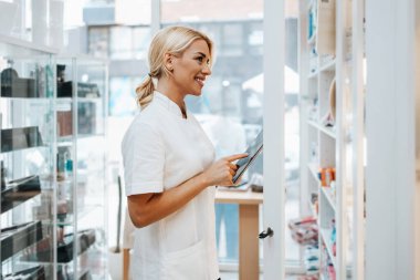 Bir eczanede çalışan genç ve çekici bir kadın eczacı. Mutlu ve gülümsüyor..