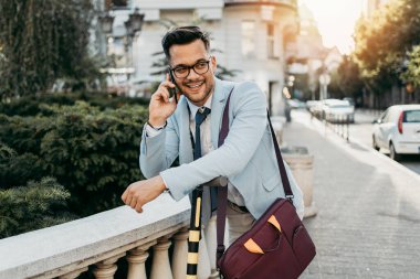 Genç modern adam akıllı telefon kullanıyor ve şehir caddesinde elektrikli scooter kullanıyor. Modern ve ekolojik ulaşım kavramı.