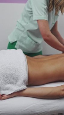 Beautiful young adult brunette receiving professional relaxation massage treatment at beauty spa salon.