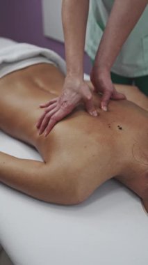 Beautiful young adult brunette receiving professional relaxation massage treatment at beauty spa salon.