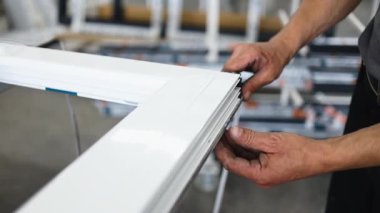 Hassas fabrika işçisi, beyaz alüminyum pencere çerçevesine siyah lastik mühür takarak, sıkı hava şartlarının profesyonelliğe ve detaylara uymasını sağlıyor.