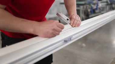 Hassas fabrika işçisi, beyaz alüminyum pencere çerçevesine siyah lastik mühür takarak, sıkı hava şartlarının profesyonelliğe ve detaylara uymasını sağlıyor.