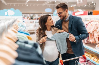 Çekici, orta yaşlı bir çift yeni bebekleri için elbise ve eşyalar almaktan zevk alıyor. Bebek dükkanında ya da dükkanda güzel bir çift. Bebek konsepti bekleniyor..