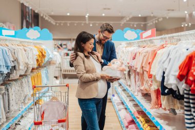 Çekici, orta yaşlı bir çift yeni bebekleri için elbise ve eşyalar almaktan zevk alıyor. Bebek dükkanında ya da dükkanda güzel bir çift. Bebek konsepti bekleniyor..