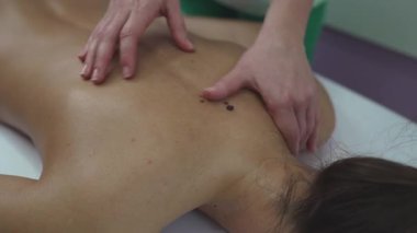 Beautiful young adult brunette receiving professional relaxation massage treatment at beauty spa salon.