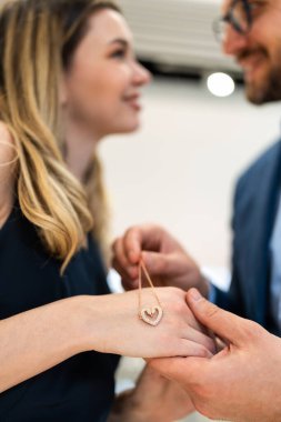 Man gifting a sparkling heart necklace to his partner, an intimate romantic moment of surprise and joy celebrating love, connection and a special occasion together