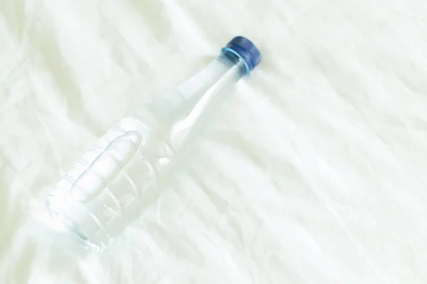 Closeup pure water bottle on white bed for healthy care and medical concept, selective focus