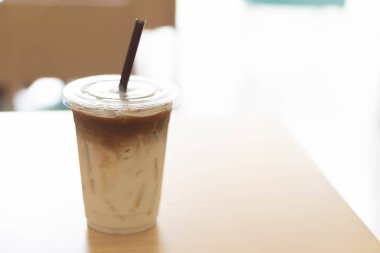 Closeup plastik bardak buzlu kahve kapıdan, seçici odak gelen ışık üzerinde ahşap tablo