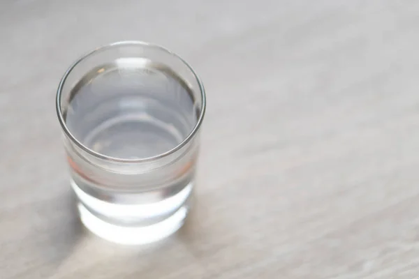 Glass of water on wood table with light in the morning, healthy care concept, selective focus