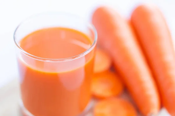 特写镜头顶部查看一杯胡萝卜汁和新鲜胡萝卜与超过光 选择性焦点 — 图库照片