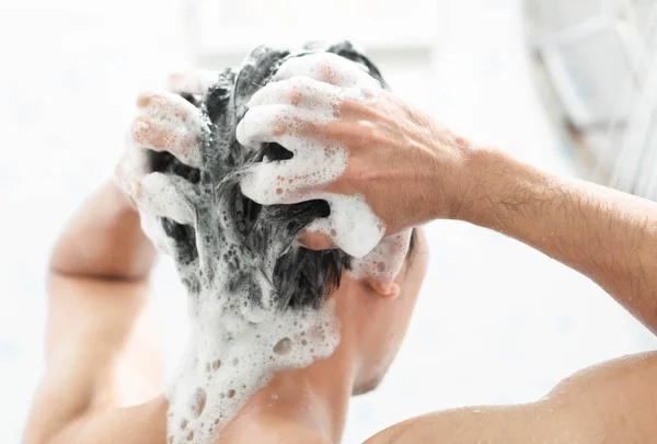 Closeup jovem homem lavar o cabelo com xampu no banheiro — Fotografia de Stock