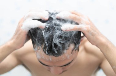 Banyo, sağlık kavramı, seçici odak şampuanla saç yıkama Closeup genç adam