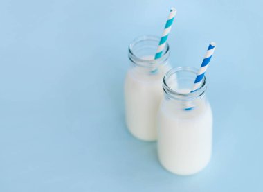Açık mavi arka planda saman ile bir şişe taze süt, sağlıklı yiyecek kavramı