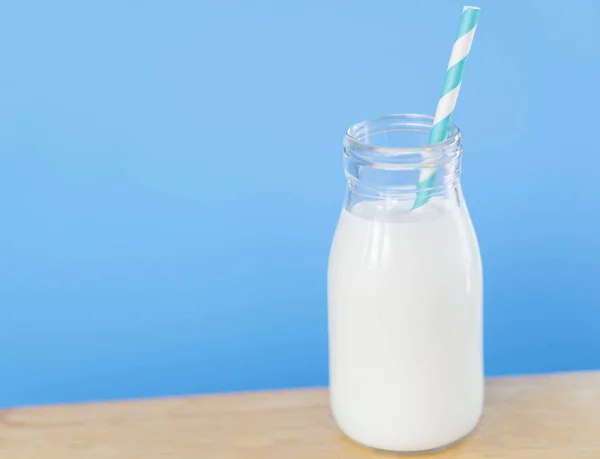 Egy üveg friss tej szalmával világoskék alapon, egészséges étel koncepció — Stock Fotó