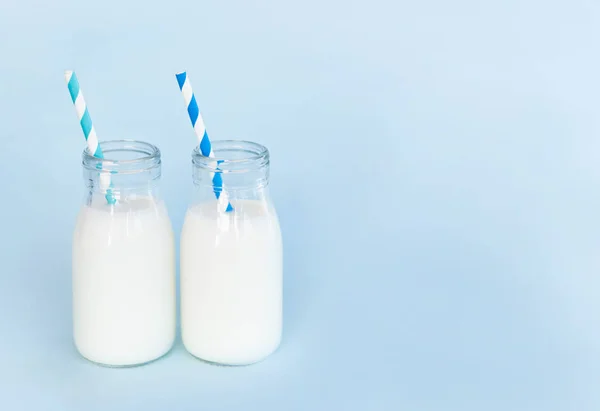 Пляшка свіжого молока з соломою на світло-блакитному фоні, концепція здорового харчування — стокове фото