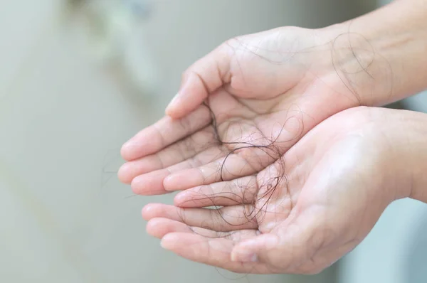Выпадение волос на женской руке в ванной комнате — стоковое фото