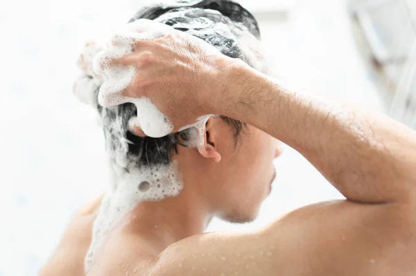 Vértes fiatalember a hajmosás samponnal, fürdőszoba, egészségügyi koncepció, szelektív összpontosít — Stock Fotó