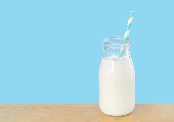Fles verse melk met stro op licht blauwe achtergrond met Kopieer ruimte, voedsel gezond concept — Stockfoto
