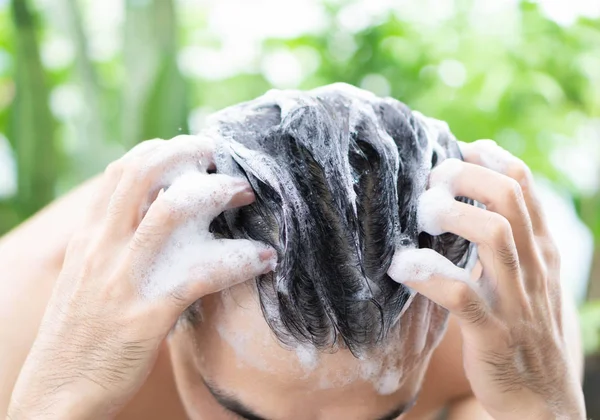 Closeup jovem homem lavar o cabelo com shampoo ao ar livre, conceito de cuidados de saúde, foco seletivo — Fotografia de Stock