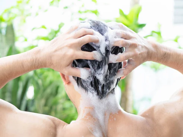 Closeup jovem homem lavar o cabelo com shampoo ao ar livre, conceito de cuidados de saúde, foco seletivo — Fotografia de Stock