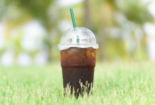 Close up vidro de café americano de gelo com fundo de natureza grama verde, foco seletivo — Fotografia de Stock