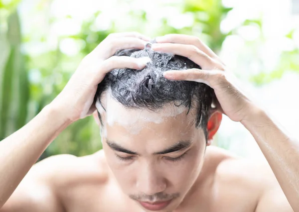 Closeup young man washing hair with shampoo from outdoor, health care concept, selective focus