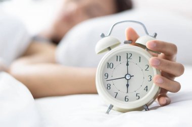 Yatak ve el tutma alarmı saat, uyanma zamanı üzerinde uyuyan kapatmak kadın