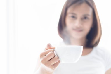 Pencere, seçici odak ışığında sıcak kahve bir fincan tutan closeup kadın