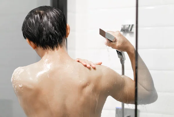 Closeup pohledný asijský muž se sprchou v koupelně, selektivní zaměření — Stock fotografie
