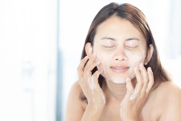 Közelkép nő látszó tükör a tükörben mosás arc hab a fürdőszobában, egészségügyi ellátás és szépség koncepció — Stock Fotó