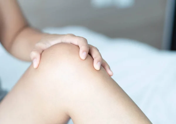 Gros plan femme main tenant genou avec douleur au lit, soins de santé et concept médical — Photo
