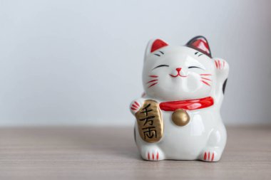 Maneki neko şanslı kedi elimizdeki metni gösterir yani ahşap masa zemininde zengindir, odak noktasını seçin