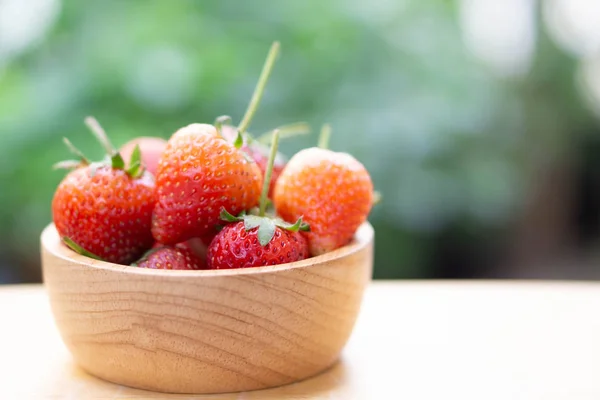 Gros plan fraise rouge dans un bol en bois avec fond vert nature, mise au point sélective — Photo