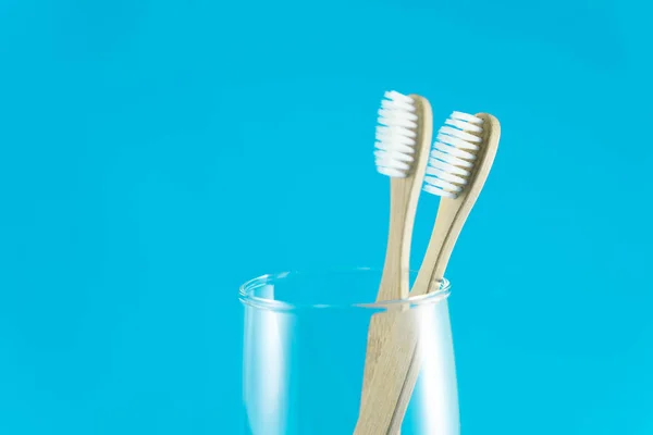 Cepillo de dientes de madera en vidrio con fondo azul, enfoque selectivo — Foto de Stock
