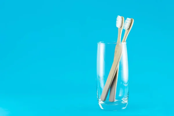 Деревянная зубная щетка в стекле с голубым фоном, селективная фокусировка — стоковое фото