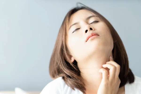 Closeup woman holding neck with pain after waking up on bed, healthy care and medical concept