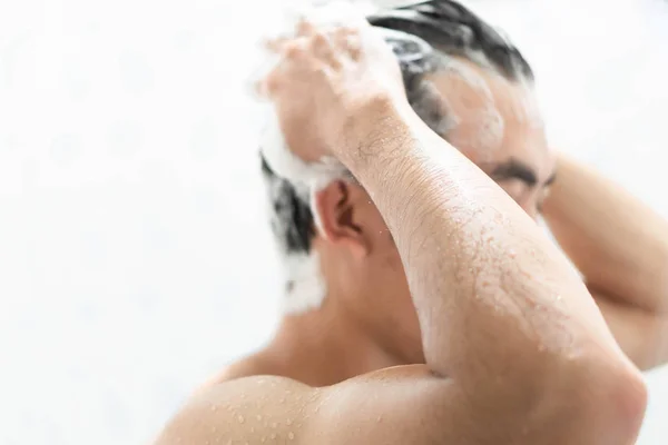 Nahaufnahme junger Mann beim Haarewaschen mit Shampoo im Badezimmer, Gesundheitskonzept, selektiver Fokus — Stockfoto