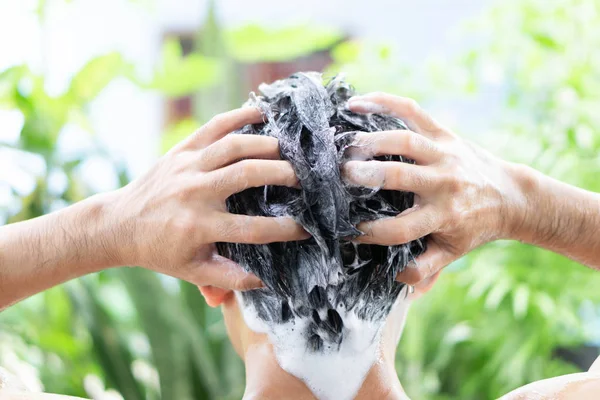 Closeup jovem homem lavar o cabelo com shampoo ao ar livre, conceito de cuidados de saúde, foco seletivo — Fotografia de Stock