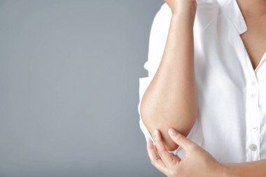 Gri arka plan, sağlık ve tıbbi kavram ile ağrı ile dirsek tutan closeup kadın el