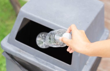 Çöp plastik şişeyi geri dönüşüm çöp kutusuna tutarak el ele kapama, seçici odak