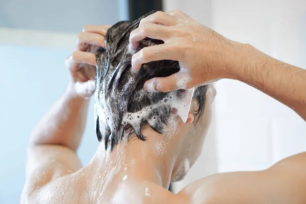 Nahaufnahme junger Mann beim Haarewaschen mit Shampoo im Badezimmer, Vintage-Ton, selektiver Fokus — Stockfoto