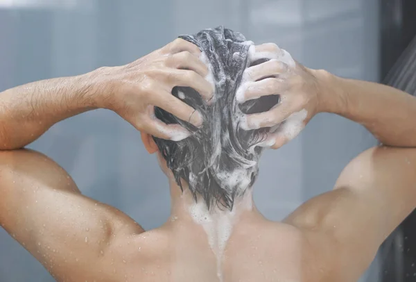 Closeup jovem homem lavar o cabelo com xampu no banheiro, tom vintage, foco seletivo — Fotografia de Stock